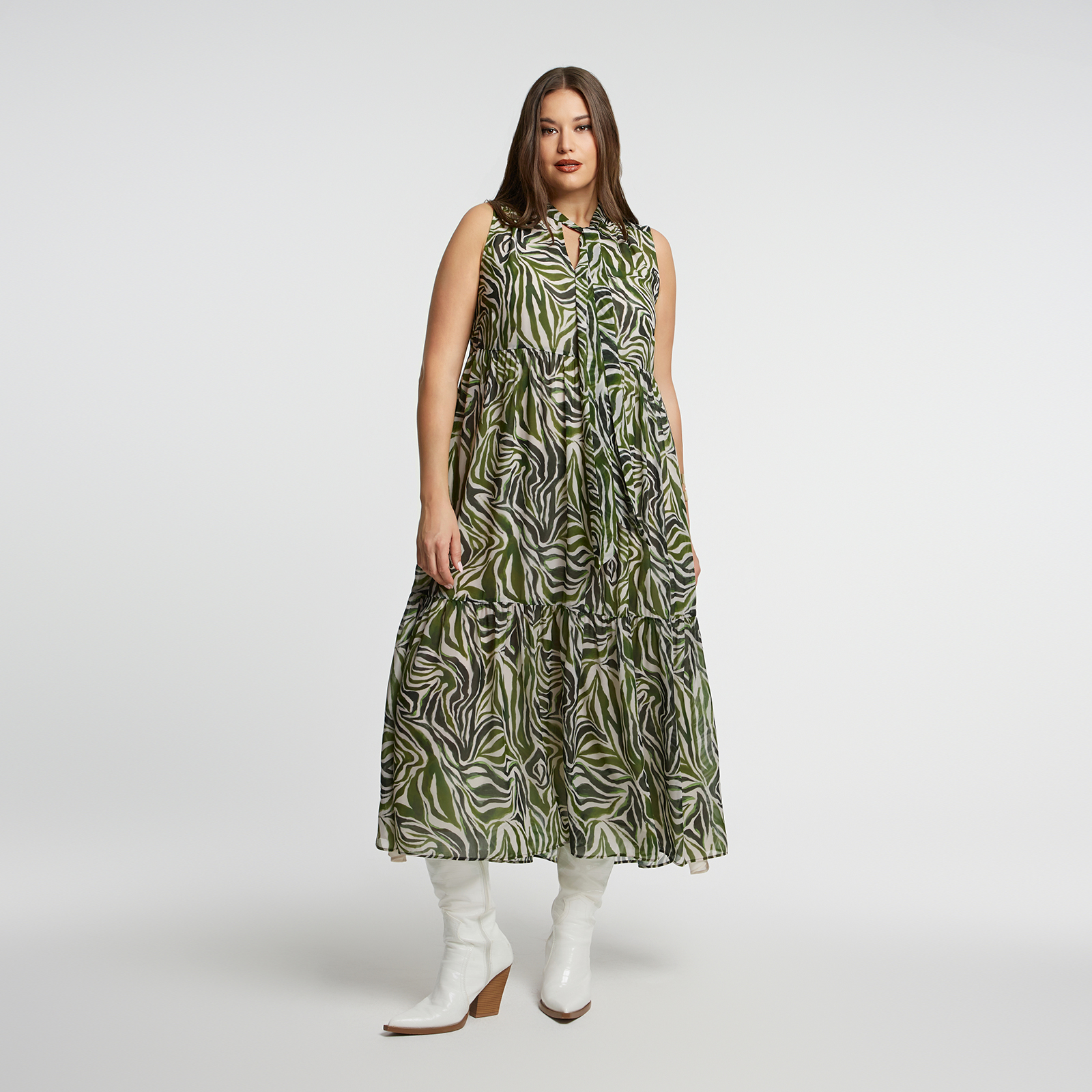 Ένα φόρεμα που ξεχωρίζει με το jungle-inspired print του σε πράσινους και γήινους τόνους. Το αμάνικο σχέδιο και το ελαφρύ ύφασμα προσφέρουν άνεση και στυλ για τις ζεστές μέρες ή τις καλοκαιρινές βραδιές. Το τελείωμα με πτυχώσεις χαρίζει αέρινη κίνηση και μια μοντέρνα πινελιά. ● Φτιαγμένο από ανάλαφρο πολυεστέρα ● Εντυπωσιακό ζεβρέ σχέδιο σε γήινες αποχρώσεις ● Άνετη γραμμή χωρίς μανίκια ● Δέσιμο στον λαιμό για κομψή εμφάνιση Μήκος (κέντρο της πλάτης): 137 εκ 100%POLYESTER Το μοντέλο έχει ύψος 1,80 εκ. και φοράει S/M